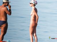Nudist family relaxes at the beach during a hot summer day