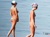 Nudist family relaxes at the beach during a hot summer day