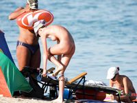 Nudist family relaxes at the beach during a hot summer day