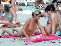 This dazzling blonde sits on the rocky beach topless and enjoys her day, unaware she's being filmed