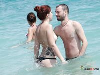 Two Nude Women Walk the Beach With the Ocean Behind Them
