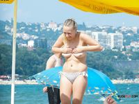 Nudist girl relaxes while she lyes naked at the beach and read a magazine