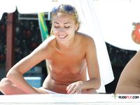 Nudist girl relaxes while she lyes naked at the beach and read a magazine