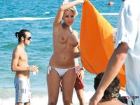 She sits in the sand sunbathing her large natural breasts with sexy tan lines