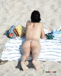 Debout nue sur le sable, le piercing au nombril dans la lumière