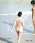 Debout nue sur le sable, le piercing au nombril dans la lumière