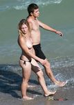 Two Topless Women Standing in Clear Sea Water