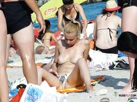 Playful nudist adult has fun with her friends at a beach during a hot summer day 2