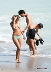 Topless procházka u oceánu v pruhovaném spodním dílu bikiny