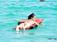 One Woman Topless at the Beach Holding a Pale Towel