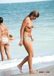 Zonnig topless strandmoment als ze uit ondiep water stapt
