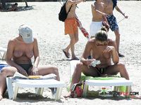 Яркая поза топлес среди расслабленных загорающих