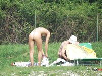 Two Nude Adults Standing Together in a Grassy Outdoor Setting