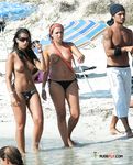 En la arena, topless con las olas del océano detrás