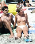 En la arena, topless con las olas del océano detrás