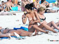 Lotion on Skin at a Topless Beach While Others Relax Nearby