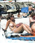 Abbronzatura nuda rilassata sulla sabbia tra altri bagnanti