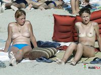 Two Nude Women Walk Through Shallow Water at the Beach
