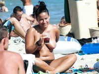 Adorable slim babe enjoys having a sunbathe with her friend on a naked beach