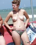 Twee naturisten praten op het strand terwijl één haar hoed verstelt