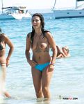 Tatuada e topless enquanto atravessa as águas rasas do mar