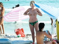 One Woman Topless on a Beach Towel by a Stone Wall