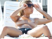 She sits among other people and sunbathes listening to music with her perky, natural tits on display