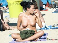 Dos mujeres topless entre sombrillas de colores en la arena