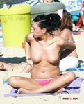 Dos mujeres topless entre sombrillas de colores en la arena