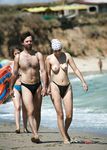 Cueca estampada e passos em conjunto na caminhada de casal na praia nudista