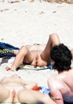 Vorgebeugt im Sand, während andere auf Handtüchern liegen