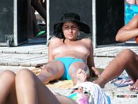 Bronzage nu sur une serviette sur une plage de sable animée