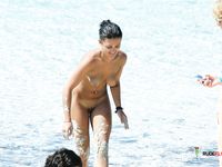 Two hot chicks are enjoying playing ball on a sandy beach in a nudist park