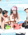 This playful brunette sits at the beach and sunbathes her beautiful, perky breasts 4