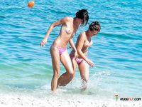 Clear Blue Water Frames a Topless Beach Stroll for Two