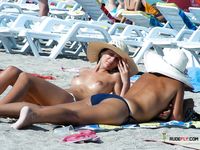 Clear Blue Water Frames a Topless Beach Stroll for Two