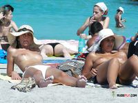Clear Blue Water Frames a Topless Beach Stroll for Two