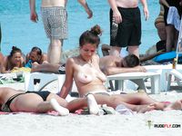 Naturist babe caught lying down and the beach and sunbathing naked