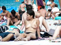 Naturist babe caught lying down and the beach and sunbathing naked