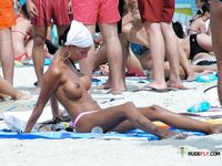 Naturist babe caught lying down and the beach and sunbathing naked