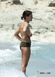 Naturist girl on a naked beach takes off her bra