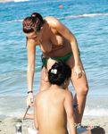 Fixing Her Hair at a Sunny Nude Beach With Clear Blue Water