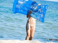Blue Air Mattress and a Nude Beach Swimmer in Shallow Water