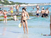 Pagaia in mano sulla riva rocciosa di una spiaggia topless