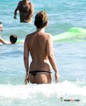 Pagaia in mano sulla riva rocciosa di una spiaggia topless