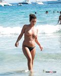 Pagaia in mano sulla riva rocciosa di una spiaggia topless