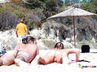 Two naturist girls are relaxing at the beach while they lay on their stomach, and the sun heats their naked asses, which attract the attention of anyone who passes by 2