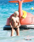 Splashing Waves Around Her Feet in Shallow Topless Beach Water