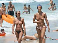 Mature brunette is joined by her husband on the beach in nudist colony as she spreads her legs to reveal her ass crack and shaved pussy 2