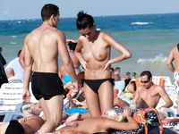 Voluptuous naturist couple enjoys their time at the beach as they go for a swim and cuddle on the towels
